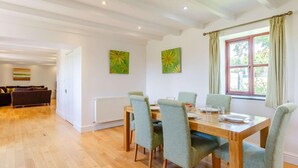 Un coin repas avec une table et des chaises en bois, un radiateur et deux tableaux accrochés au mur.