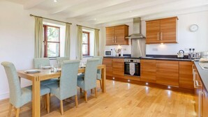 Une cuisine moderne avec des meubles en bois, une table à manger avec des chaises et un four encastré.