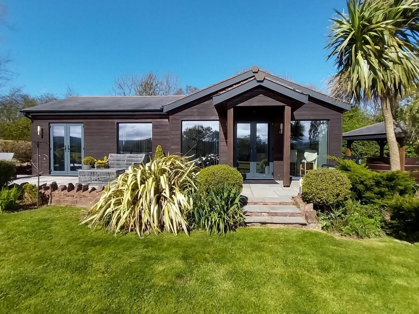A modern two-story house with a covered porch, large windows, and a well-maintained lawn.