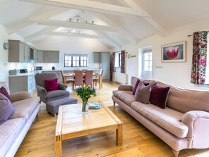 A spacious living area with a high ceiling, a dining table, and a kitchen in the background. - 3 Bed in Penzance (oc-36256) (Trescowe)
