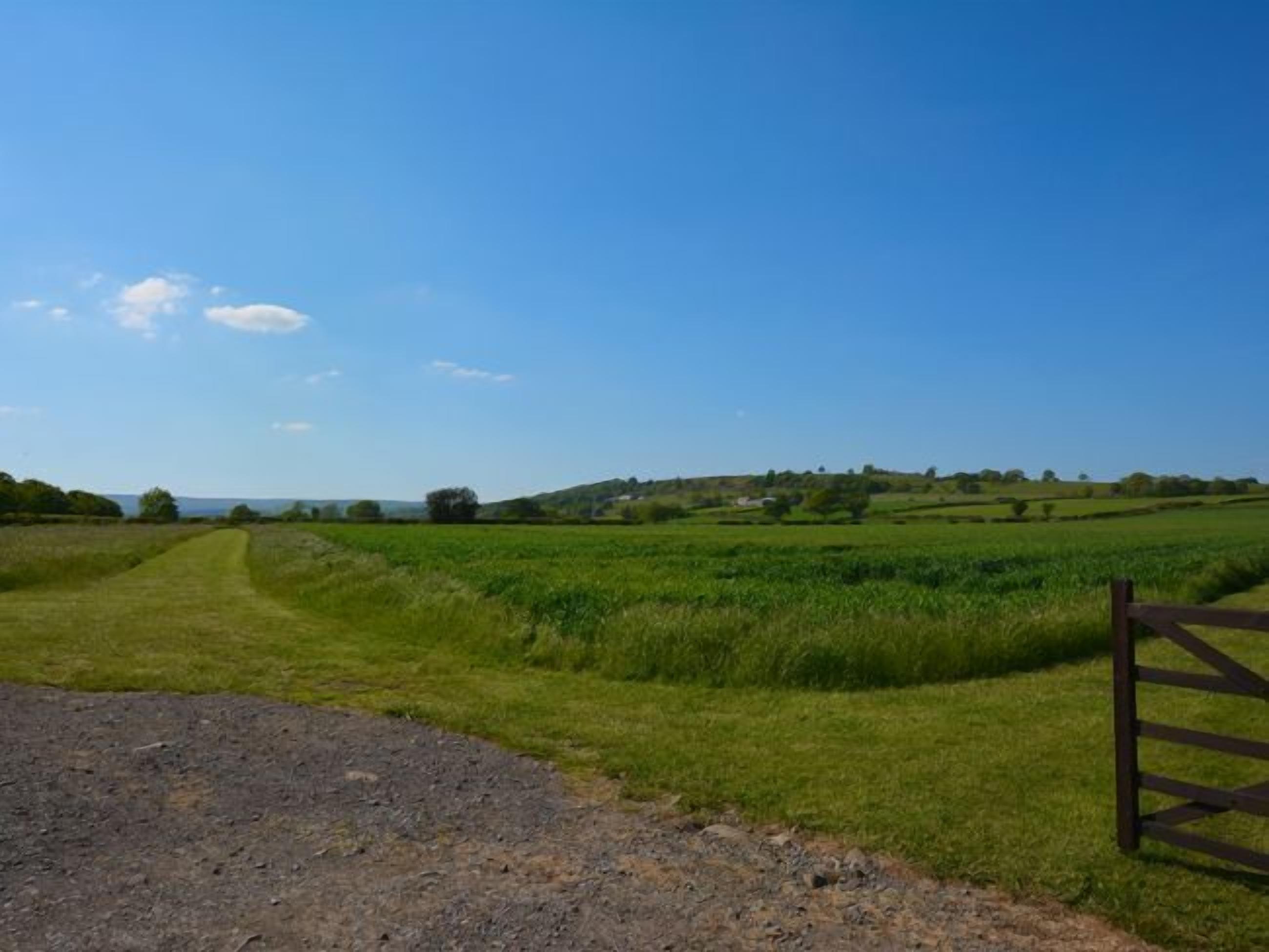 Un paysage rural avec un chemin de gravier menant à une porte en bois.