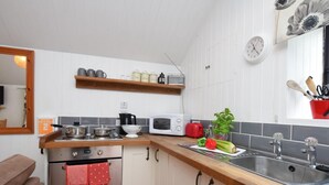 A kitchen with white cabinets, a wooden countertop, a stove, a microwave, a sink, and a window with a view. - 1 Bed in Launceston (oc-36500) (Egloskerry)