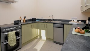 A kitchen with a built-in oven, a dishwasher, a sink, and a countertop with a toaster and a knife block. - 2 Bed in Bideford (oc-36456) (Weare Giffard)