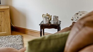 A small wooden table with a teapot and two cups, a wooden floor, and a green cushion. - 2 Bed in Bideford (oc-36456) (Weare Giffard)