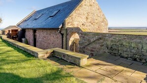 Un bâtiment en pierre doté d’un toit en pente, d’une cheminée et d’un mur en pierre.