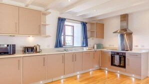 Een moderne keuken met houten kastjes, een inbouwoven en een roestvrijstalen afzuigkap.