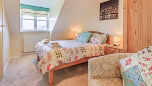 Une chambre à coucher avec un lit, une table de chevet, une chaise, une fenêtre et un tableau représentant un paysage urbain.