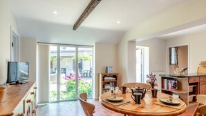 Un coin repas comprenant une table ronde, des chaises, un téléviseur et une bibliothèque.