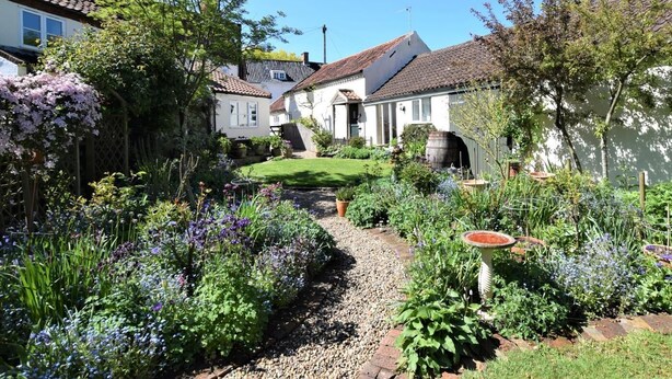 Un charmant village avec des maisons traditionnelles, un jardin bien entretenu et un chemin dégagé.