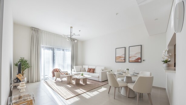 A modern living room with a sofa, coffee table, dining area, and a TV. - Bloomfields 1BR in Yas Golf Collection  (Abu Dhabi)
