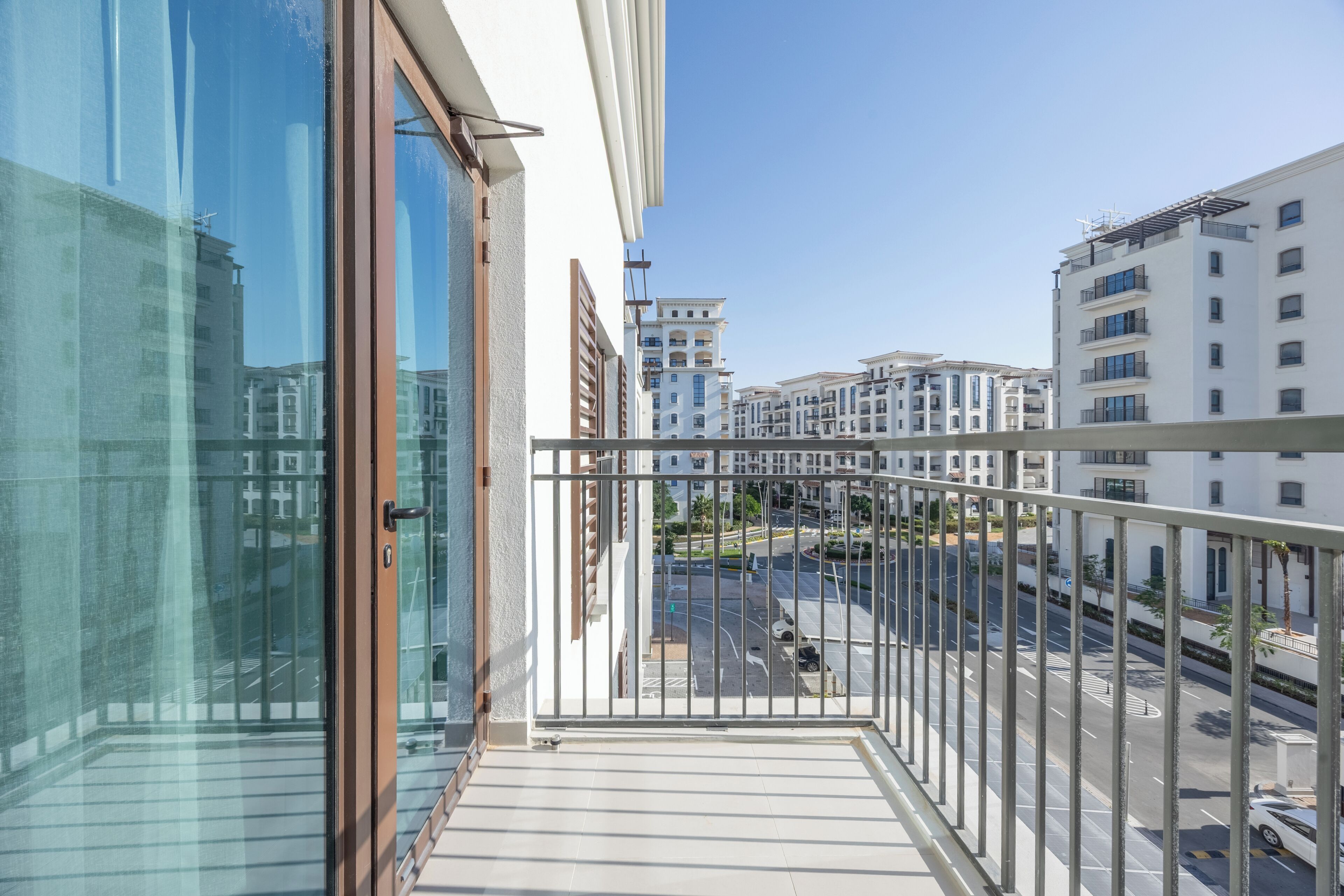 Un balcon donnant sur un paysage urbain, avec des bâtiments et une route.