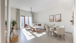 A modern living room with a sofa, coffee table, and dining area. - Bloomfields 1BR in Yas Golf Collection  (Abu Dhabi)