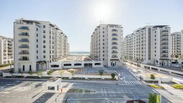 A modern apartment complex with multiple high-rise buildings, a central pedestrian area, and a clear view of the sea in the background.