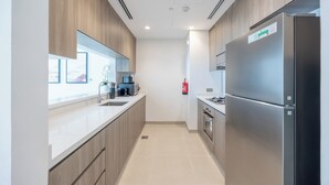 A modern kitchen with wooden cabinets, stainless steel appliances, and a window overlooking a snowy landscape. - Bloomfields 1BR in Yas Golf Collection  (Abu Dhabi)
