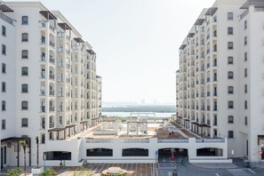 Un immeuble d’appartements moderne doté de balcons, d’une terrasse sur le toit et offrant une vue sur un plan d’eau.