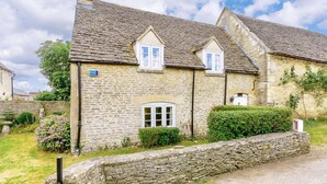 A stone house with two windows, a chimney, and a stone wall in front. - 2 Bed in Lechlade (oc-40192) (Langford)
