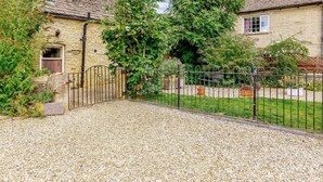 A stone building with a gravel driveway, a metal gate, and a fenced garden area. - 2 Bed in Lechlade (oc-40192) (Langford)