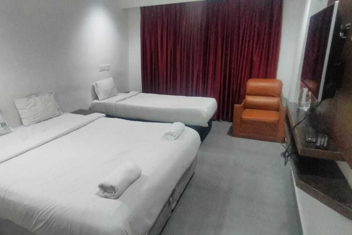 Ein Hotelzimmer mit zwei Betten, einem Fernseher und einem roten Vorhang.