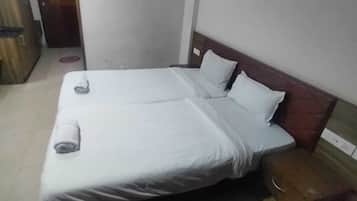 A double bed with white linens, a wooden headboard, and a small bedside table with a lamp.