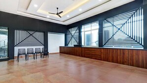 A spacious room with a high ceiling, a ceiling fan, and a reception desk with a modern design. - Hotel Southgate (Thiruvananthapuram)