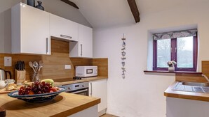 Una cocina moderna con armarios blancos, microondas, encimera de madera y ventana con vistas.