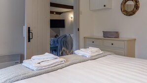 Un dormitorio con cama, cómoda, espejo y puerta que da a un baño.