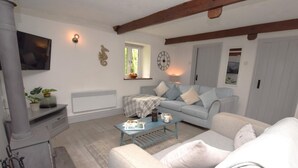 Una sala de estar con sofá, mesa de centro, televisor, chimenea y ventana.