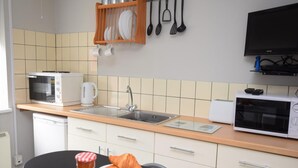 Cozinha equipada com pia, fogão, micro-ondas e um espaço para café da manhã com croissants e café.