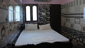 A bedroom with a bed, a window, a wall-mounted air conditioner, and patterned tiles. - sri sakthivel santhamurugan residency (Tiruvannamalai)