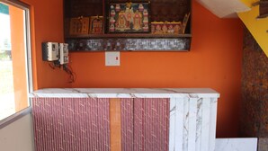 A room with a marble counter, electrical outlets, and a shelf with religious icons. - sri sakthivel santhamurugan residency (Tiruvannamalai)