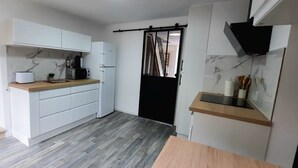 A compact kitchen with white cabinets, a wooden countertop, a black door, and a marble backsplash. - Large, renovated house in central Alsace (130 m²) (Neubois)