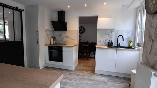 A compact kitchen with a built-in oven, a black range hood, and a window with a view. - Large, renovated house in central Alsace (130 m²) (Neubois)