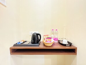 A hotel reception desk with a coffee maker, water bottles, snacks, and a basket. - Hotel on New Marine Drive Rd. Prabhupada (Puri)