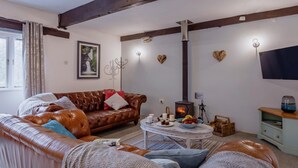 Una sala de estar acogedora con un sofá de cuero, una mesa de centro, una chimenea y un televisor.