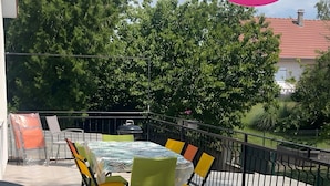 An outdoor patio with a round table and chairs, a grill, and a fence.