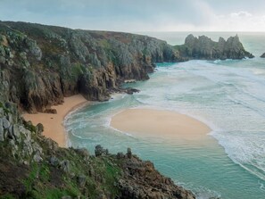 Eine Küstenlandschaft mit felsigen Klippen, einem Sandstrand und dem Meer.