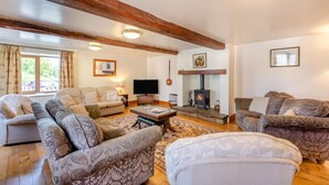 Una sala de estar acogedora con chimenea, sofás, un televisor y una guitarra.
