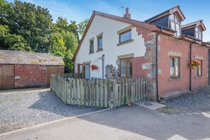 Ein zweistöckiges Haus mit weißer Fassade, einem Holzzaun und einem Schotterweg.