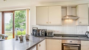 Une cuisine moderne avec des meubles blancs, un four encastré, une plaque de cuisson et un grille-pain.