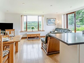 Eine moderne Küche mit Essbereich, großen Fenstern und Blick auf Grünflächen.