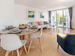 Ein modernes Wohnzimmer mit Essbereich, ausgestattet mit einer Couch, Sesseln, einem Couchtisch und Kunstwerken an den Wänden.
