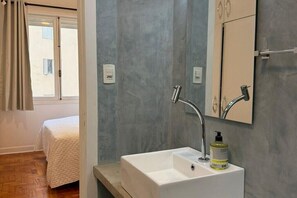 Une salle de bain avec un lavabo blanc, un miroir et un flacon de savon pour les mains.
