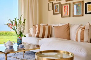Ein Wohnzimmer mit Sofa, Couchtisch, Blumen in einer Vase und gerahmten Kunstwerken an der Wand.