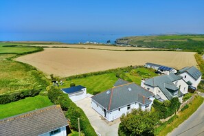 A coastal residential area with houses, a large sandy field, and a view of the sea. - The Coast House (Porthcothan Bay)