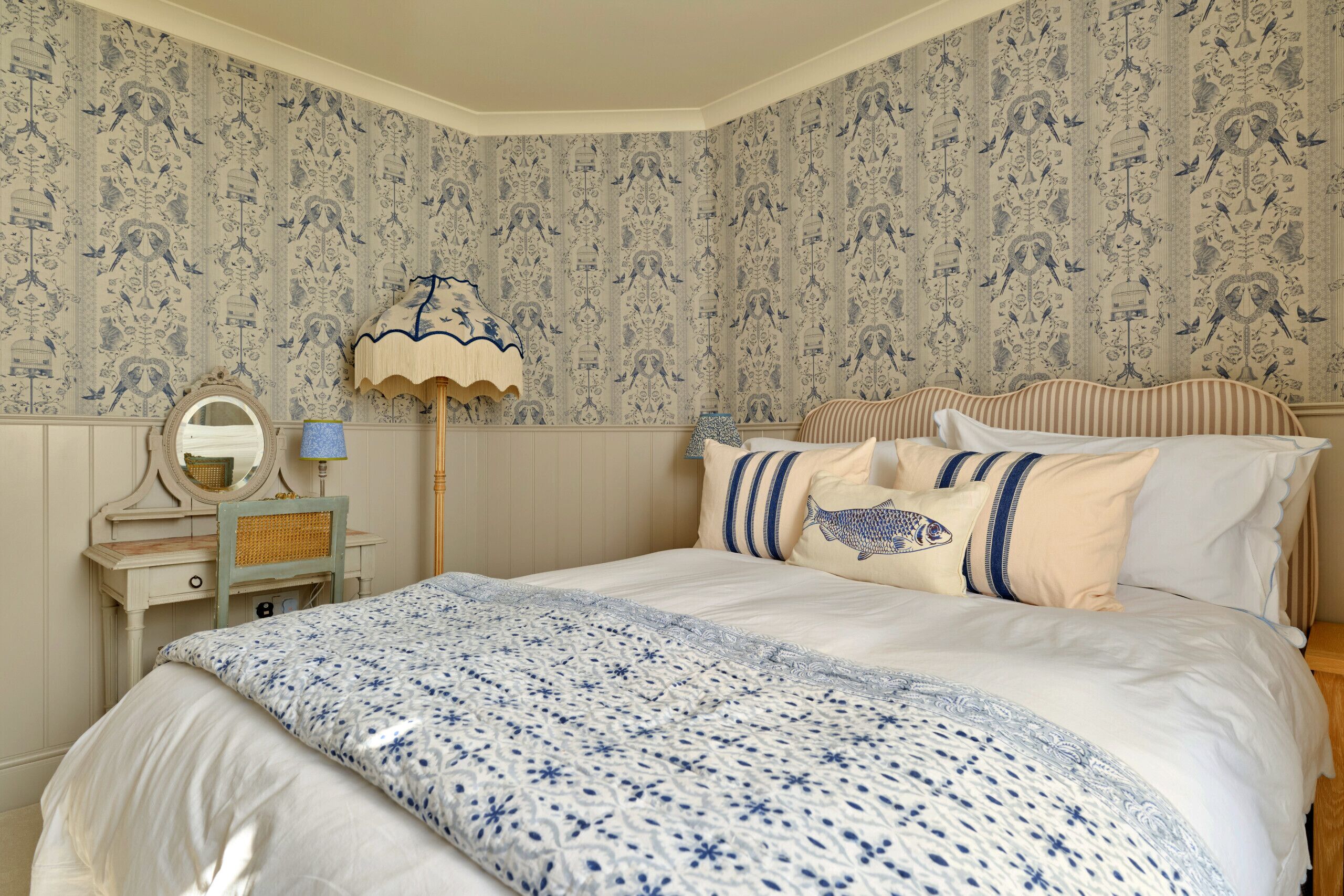 A bedroom with a bed, a dresser, a mirror, and a lamp.