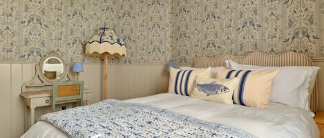 A bedroom with a bed, a dresser, a mirror, and a lamp.