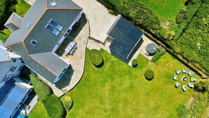 Luchtbeeld van een huis met een verharde oprit, een zonneboiler, een rond zitgedeelte en een verzorgd gazon.