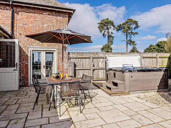 Une terrasse avec une table, des chaises, un parasol et un barbecue.