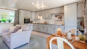 A modern kitchen with white cabinets, a dining area with a wooden table and chairs, and a cozy living room with a sofa. - 1 Bed in Holt (oc-40430) (Hempstead)