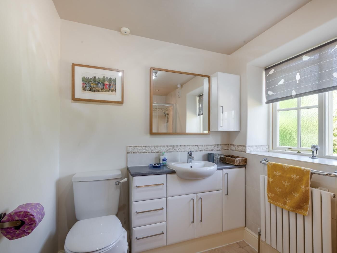 Un bagno con il water, lavabo, specchio e finestra.